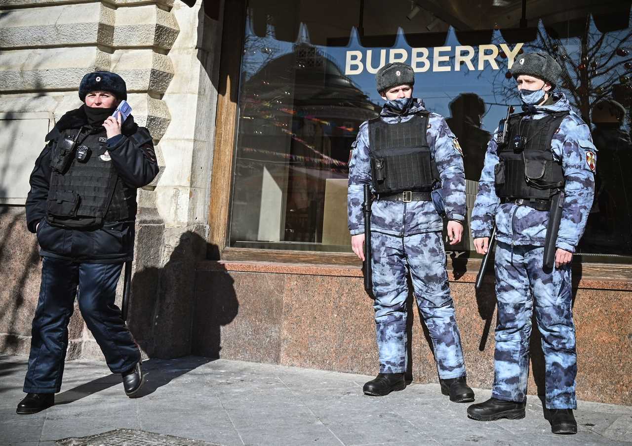 Russian law enforcement officers stand in front of a closed Burberry store in Moscow