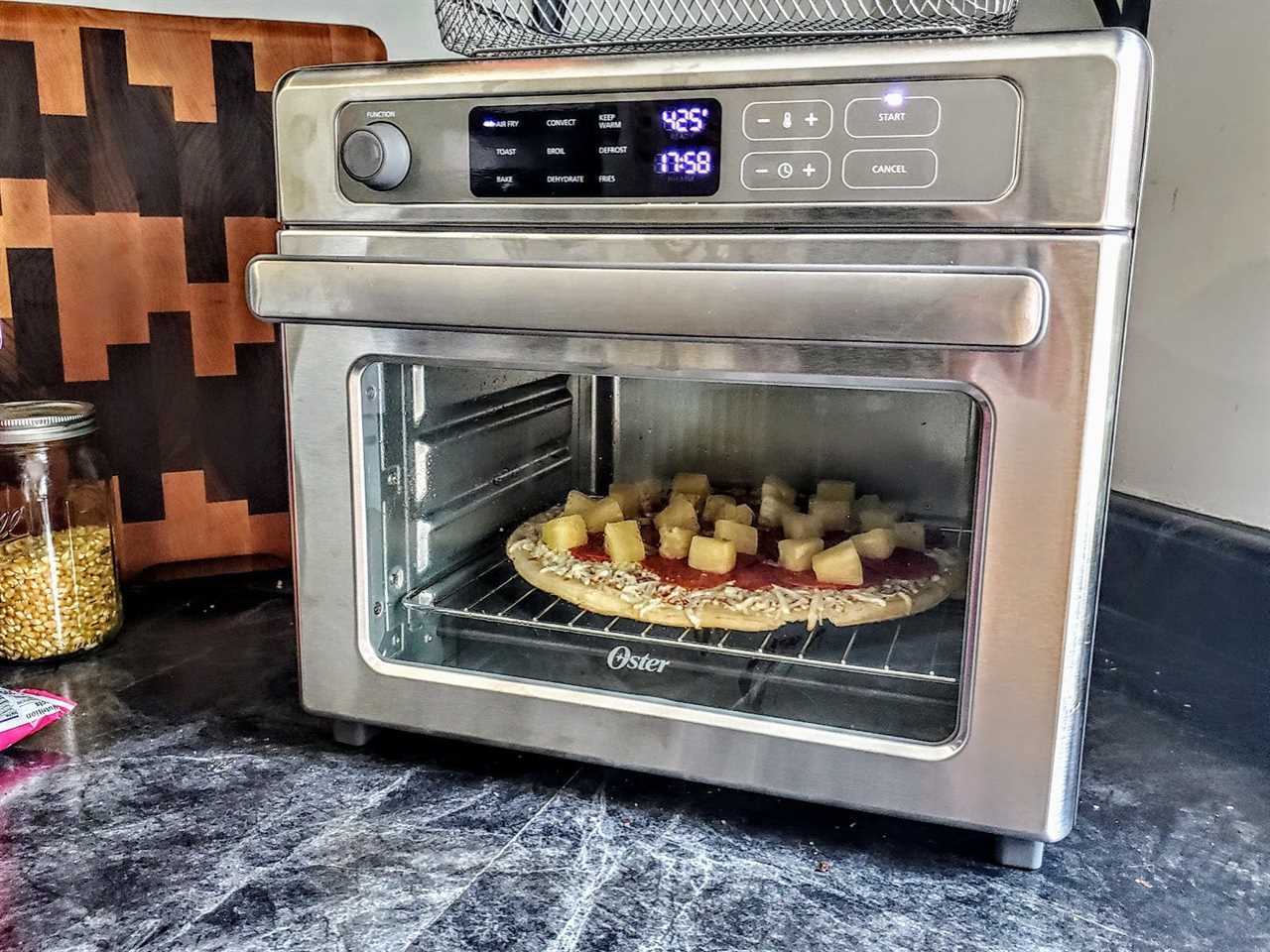 The Oster Air Fryer Oven on a counter cooking pizza at 425 degrees.