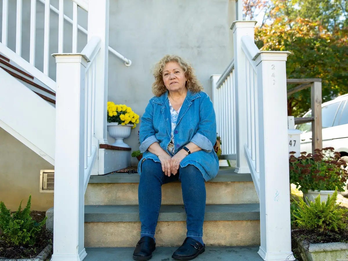 A woman poses on her front steps.