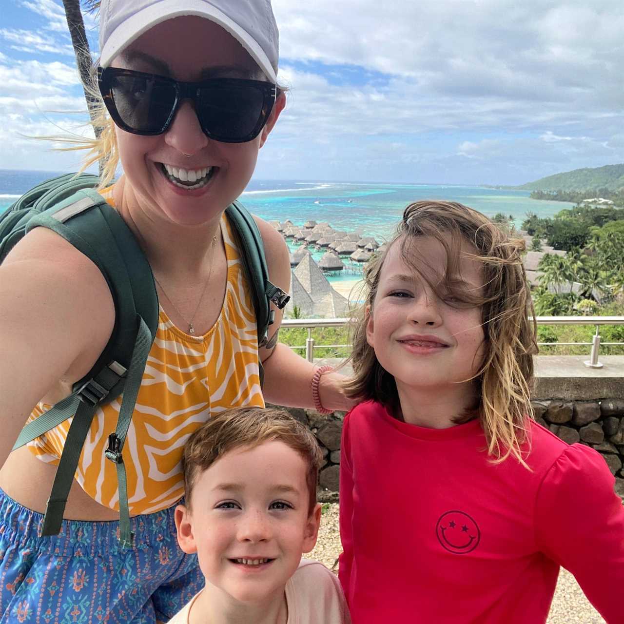 Woman and two children with stilt houses on the ocean in the background