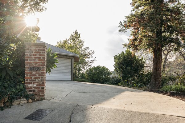 The 1950s home sits well off the road, surrounded by soaring trees and thick vegetation.