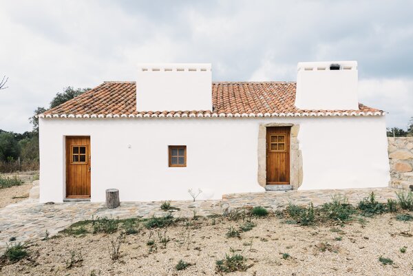 The property is surrounded by olive trees, bordered by a stream, and dotted with rock formations.