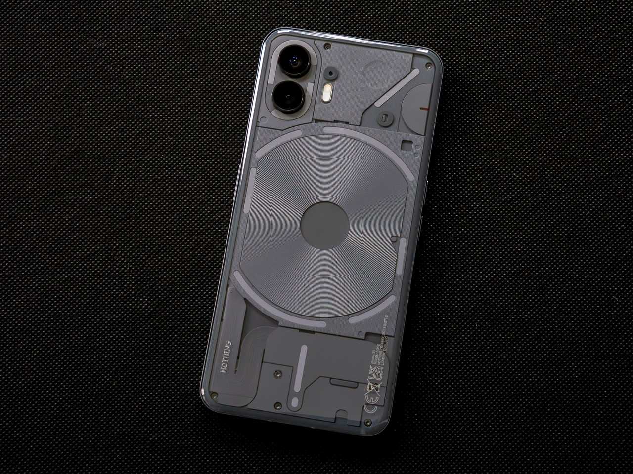 The rear of the dark gray Nothing Phone 2 against a black fabric background.