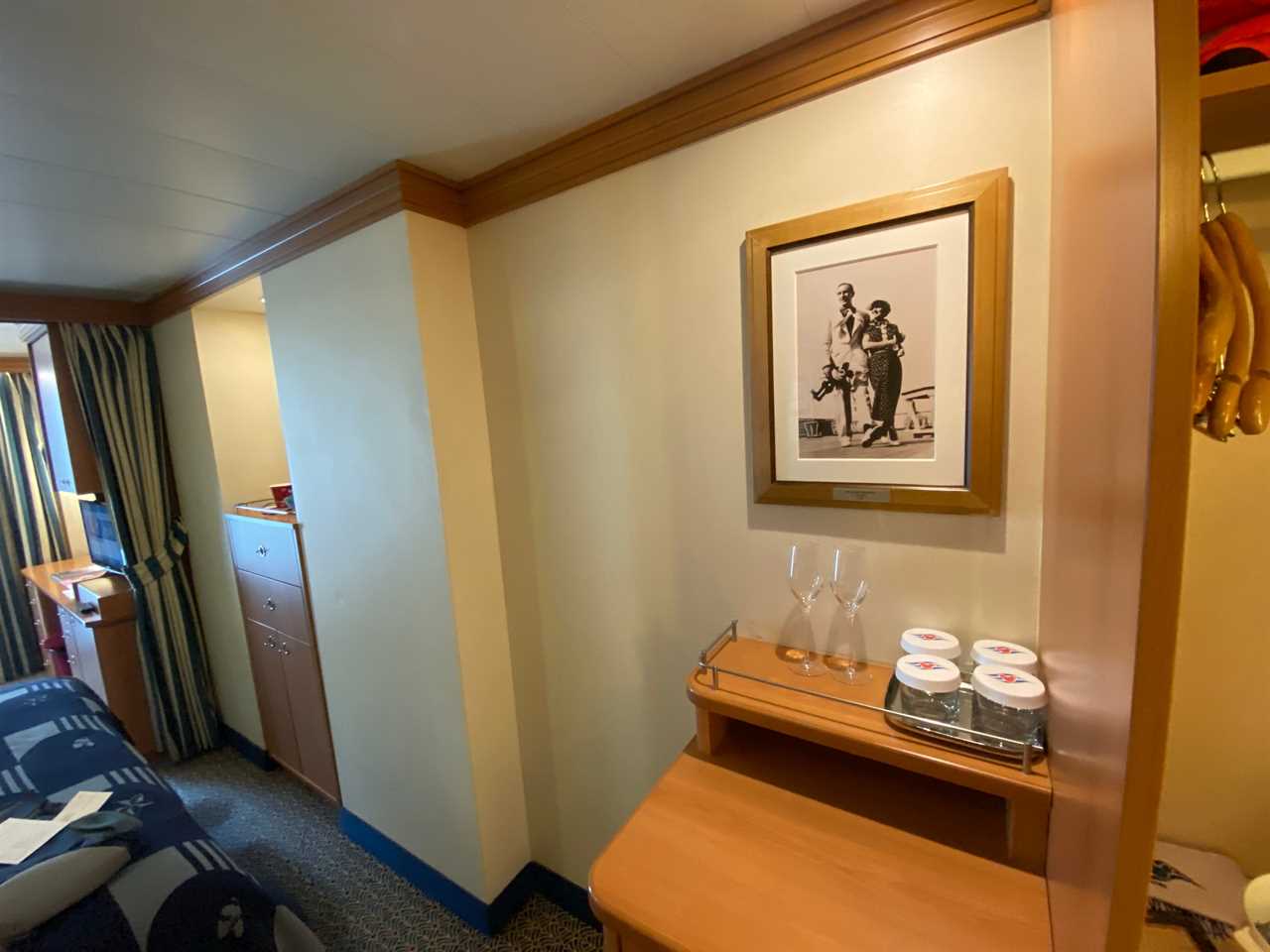 drawers and glasses on a side table under a photo of walk disney in a disney magic stateroom