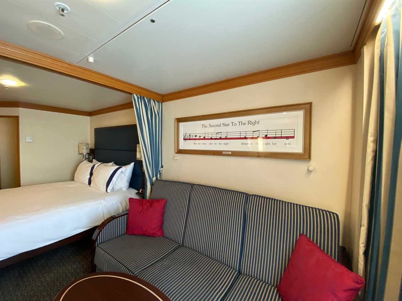 shot of a striped couch under a peter pan wall decoration in a deluxe stateroom on a disney magic cruise ship