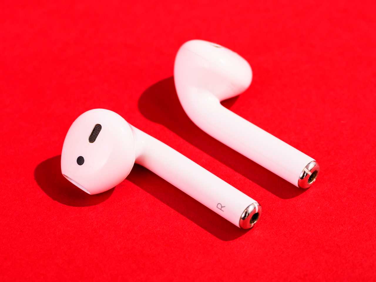 Apple Airpods displayed on a bright red background.