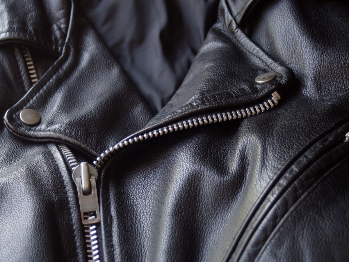 A leather jacket's buttoned collar and zipper.