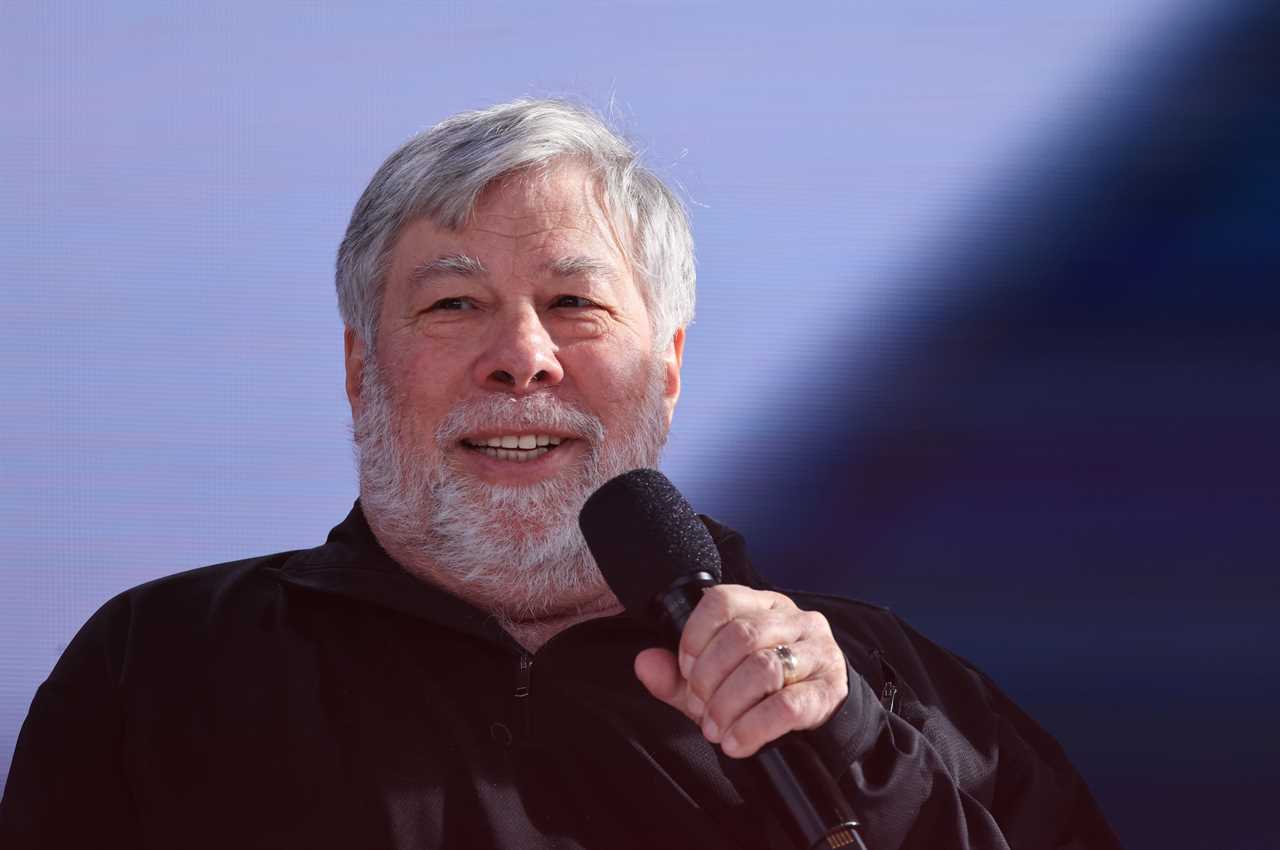 Steve Wozniak holds a microphone against a blue background