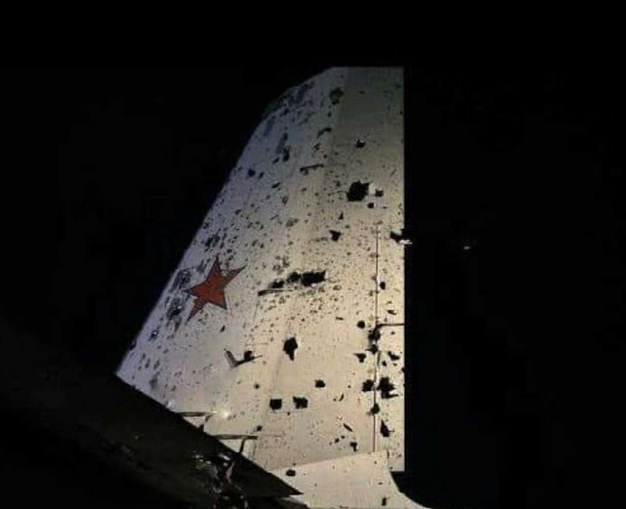 A photos shows a white aircraft wing full of holes with a red star on it