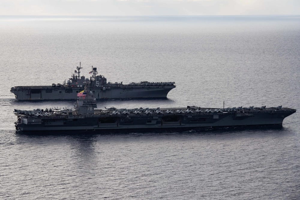 an aircraft carrier and assault ship sail side-by-side