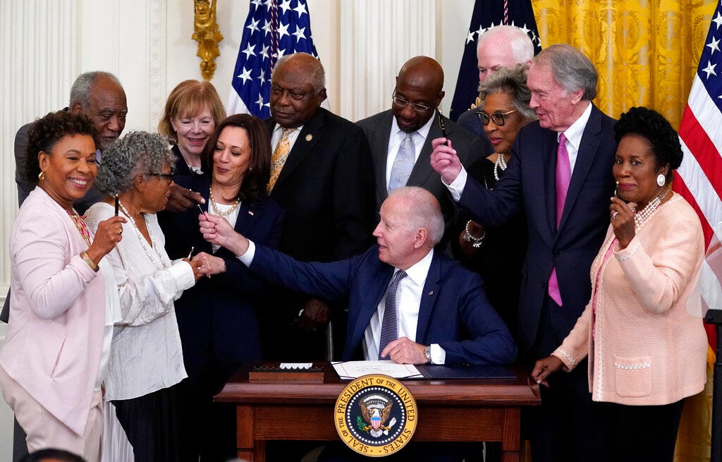 President Joe Biden hands out a pen after signing the Juneteenth National Independence Day Act, in the East Room of the White House.