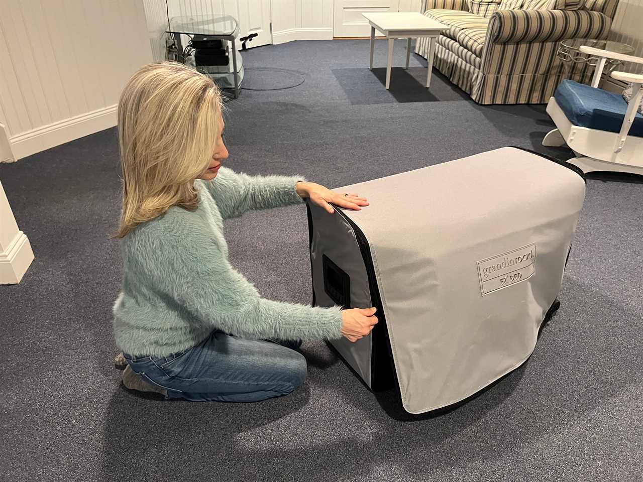 Woman on floor unzipping the EZ Bed in basement