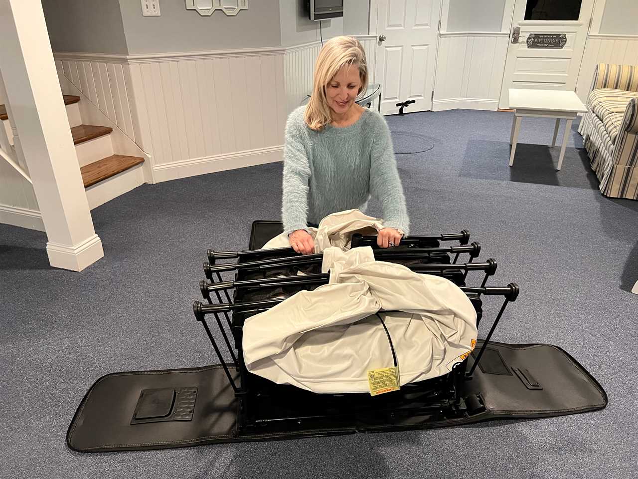 a woman pushes down the metal legs of the EZ Bed to put it back together