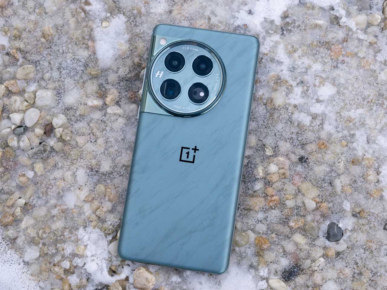 The back of the OnePlus 12 against an icy gravel background.