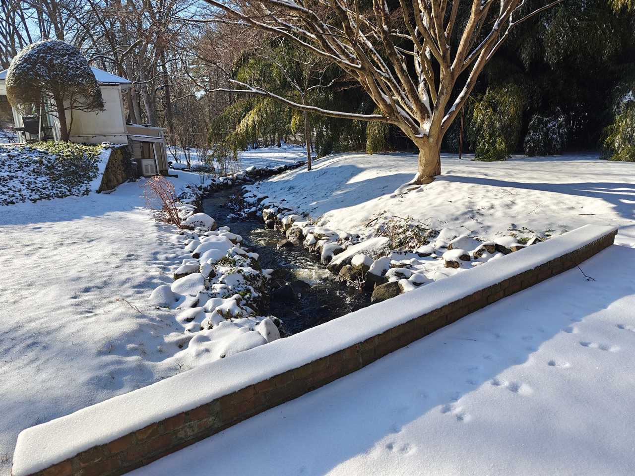 A photo of a stream and snow-covered bridge and rocks take by the OnePlus 12’s main camera.