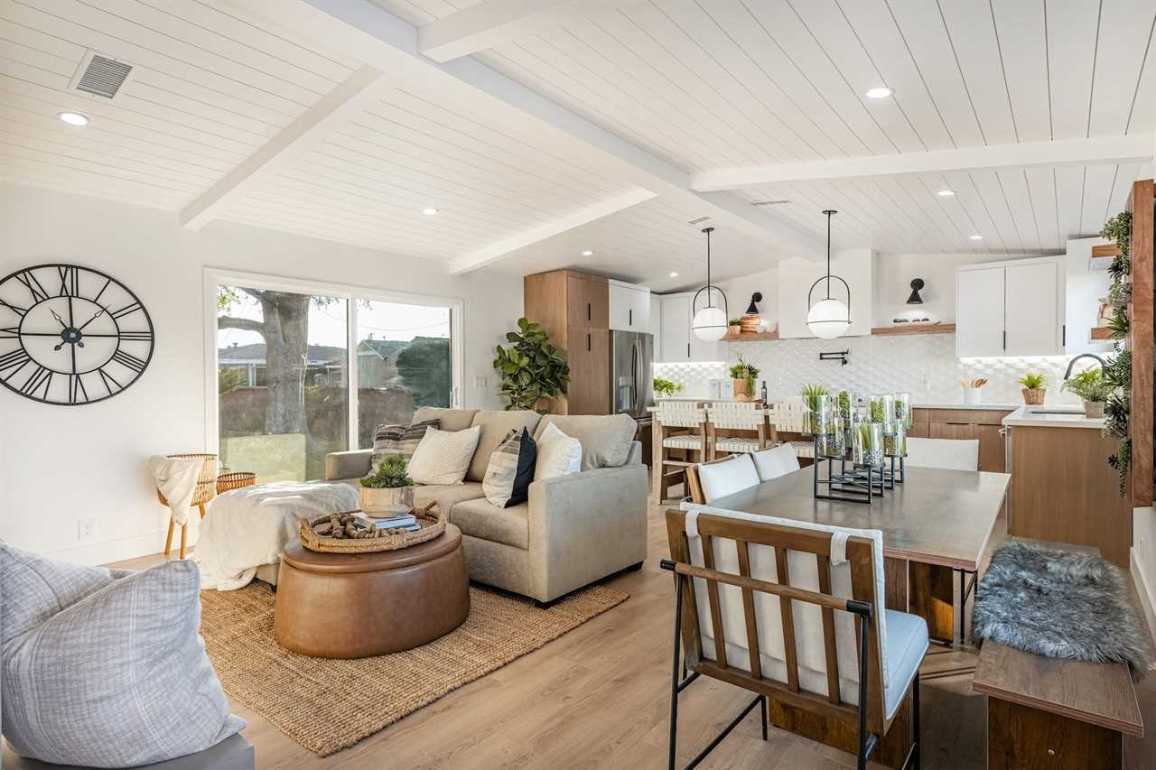 An open concept living room and kitchen with white ceilings.