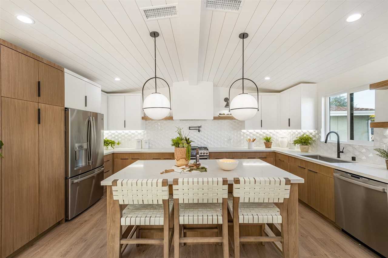 A large kitchen with an island and bar chairs.