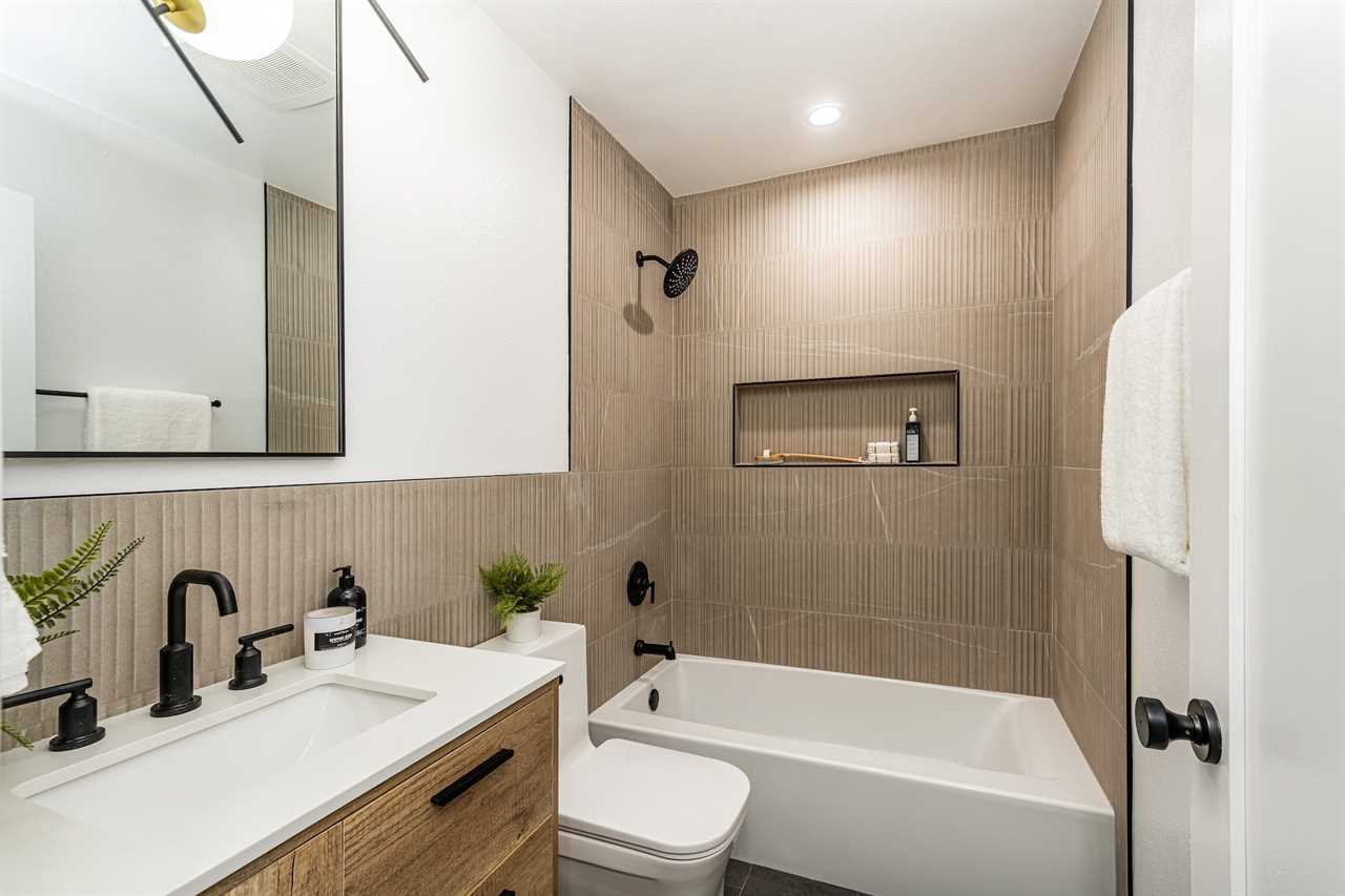 A bathroom with brown tiles on the wall and a large tub.