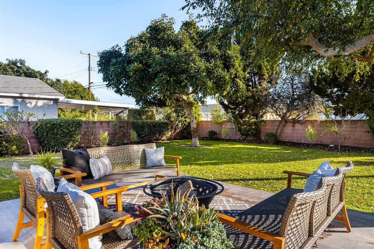 A backyard with wicker patio furniture and a brick wall surrounding it.