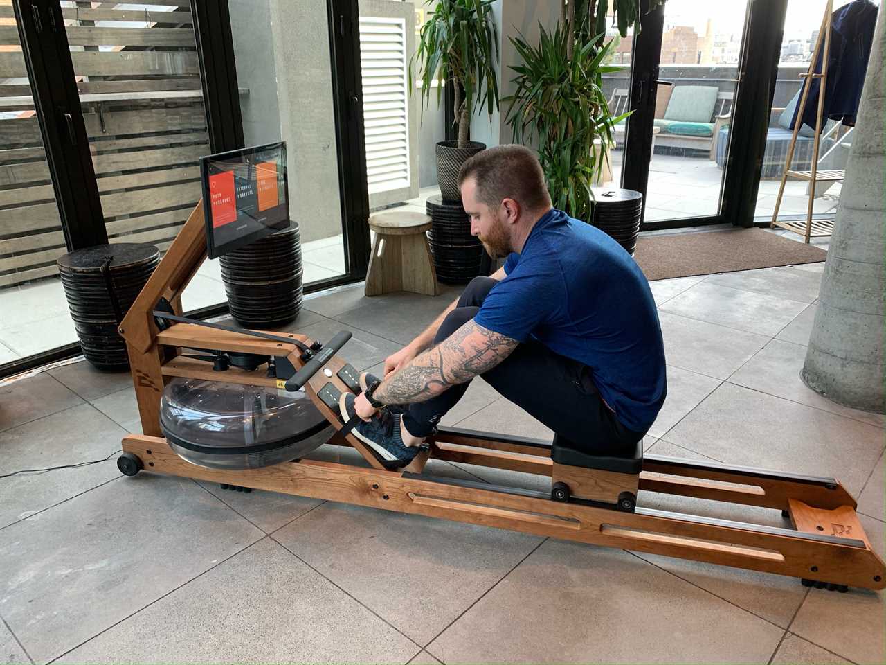 person sitting on an ergatta rowing machine in a living room.