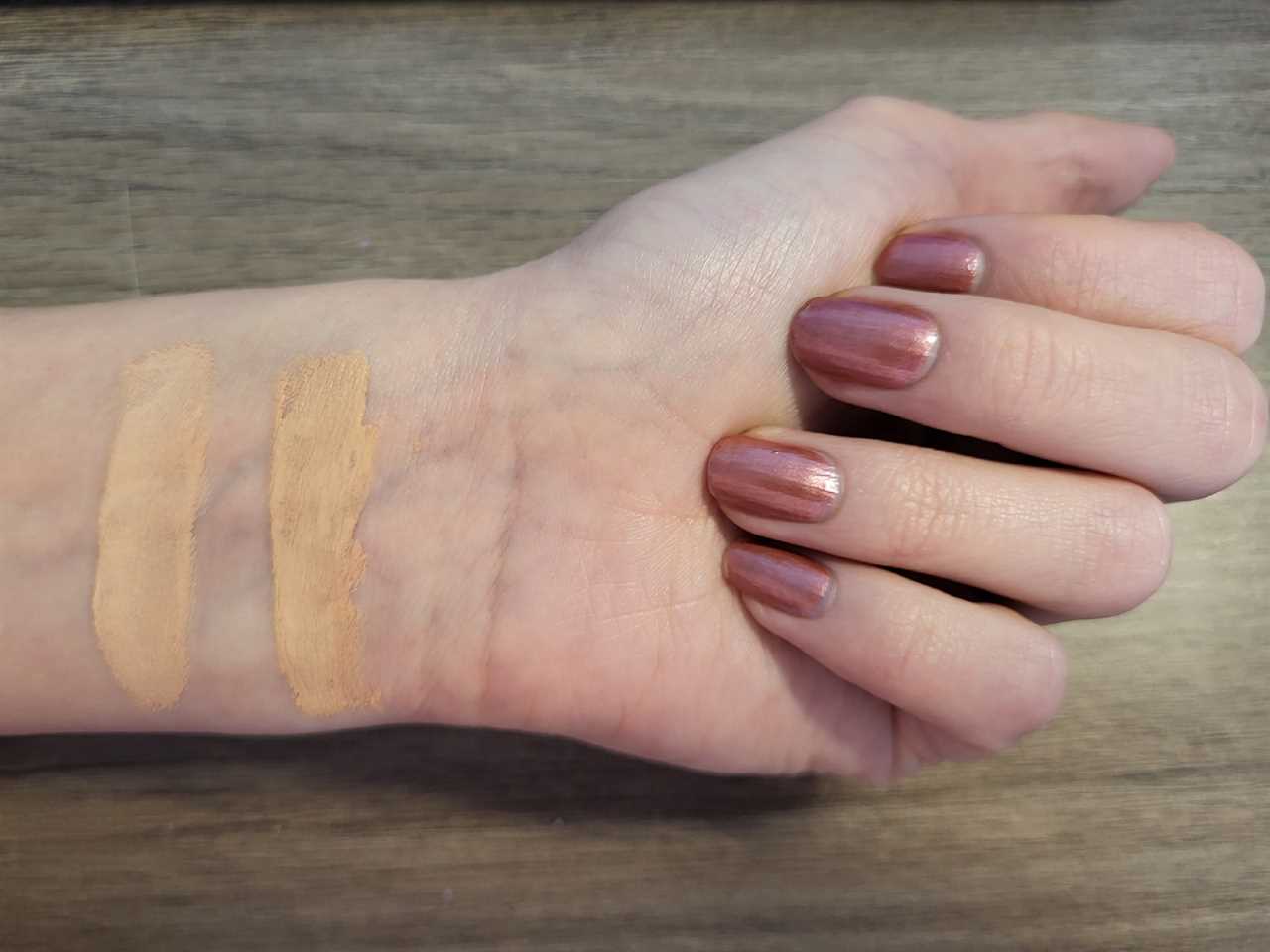 Two swatches of liquid foundation in different shades are painted on a woman’s wrist.