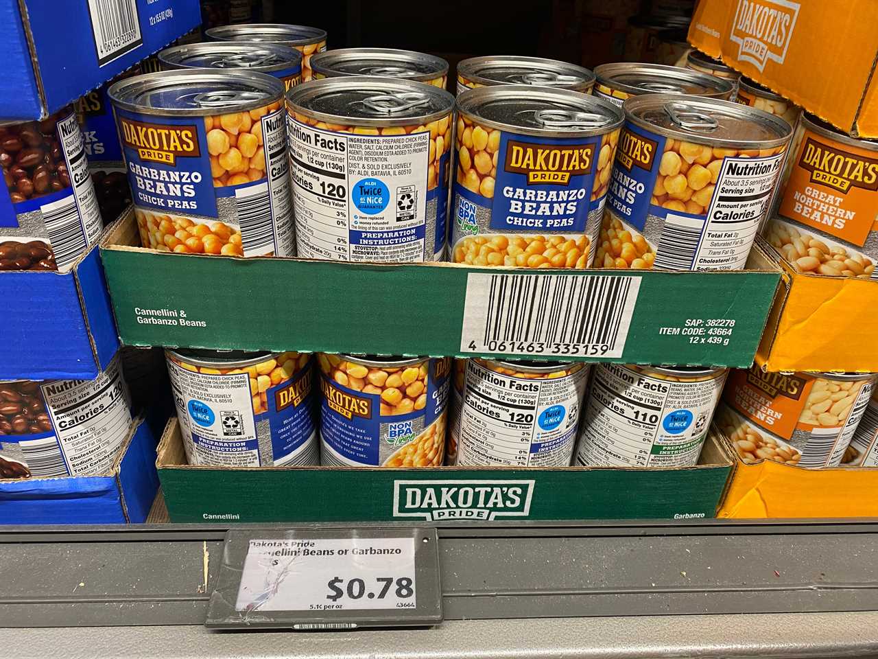 Several blue and yellow cans of garbanzo beans in green cardboard boxes at Aldi