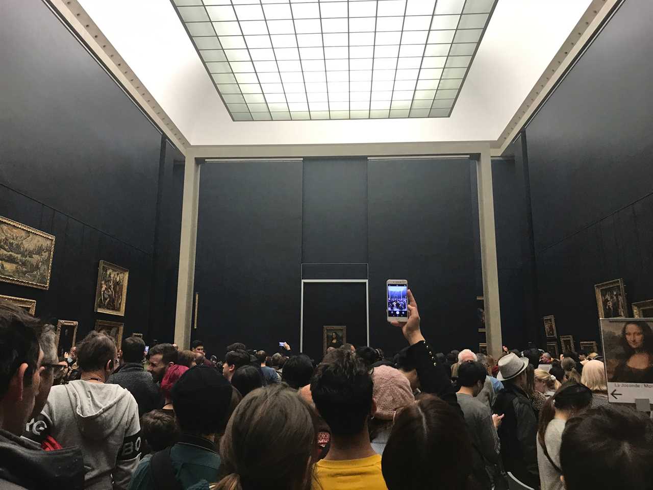 people crowded in front of the mona lisa painting at the lourve in paris