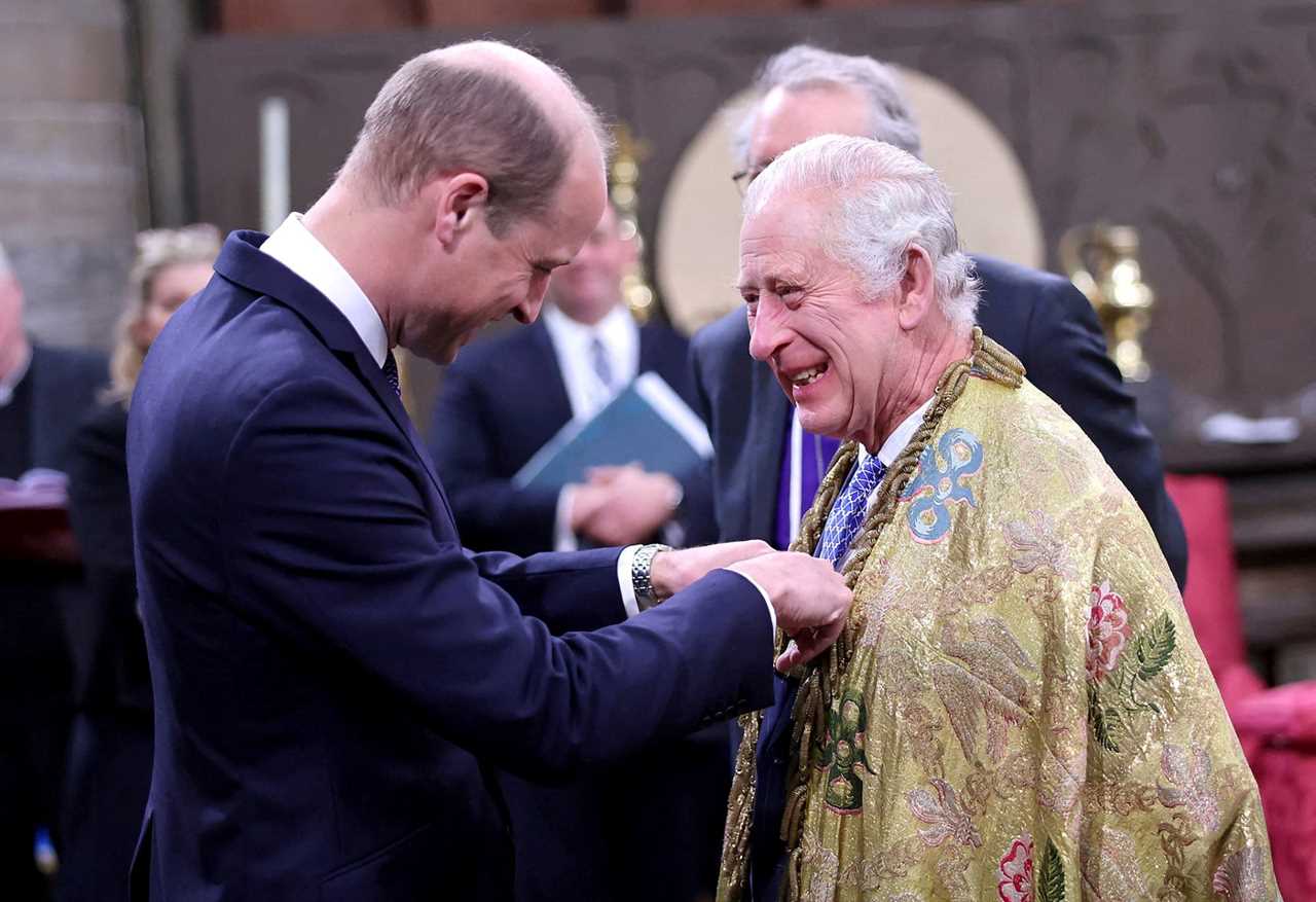 King Charles laughs as Prince William pins something to his chest.