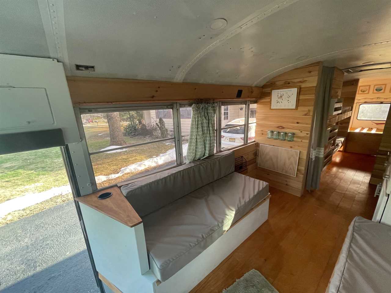 Inside of redesigned bus with gray seating, wood panelling, and white ceiling