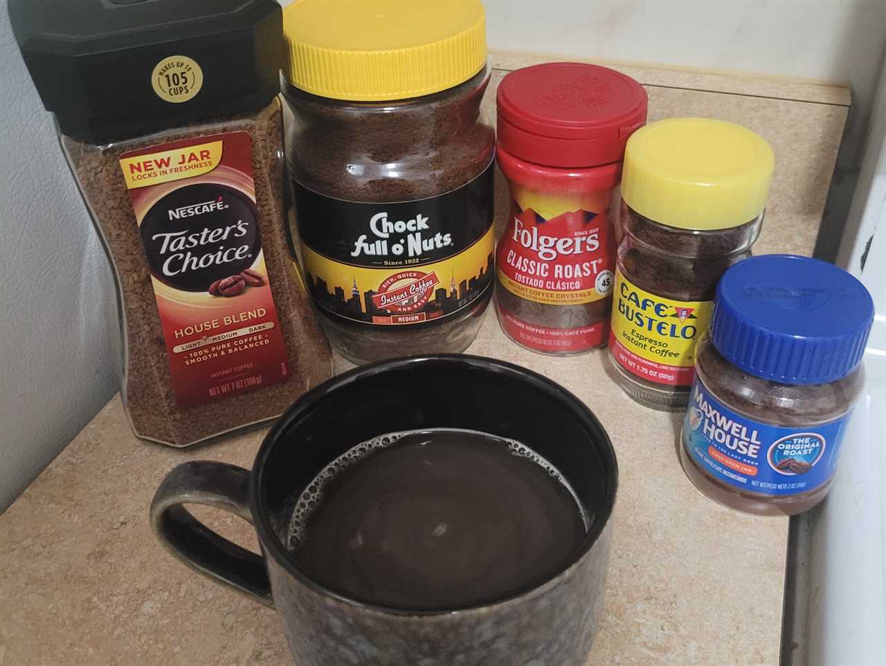 jars of instant coffee surrounding a cup of prepared coffee