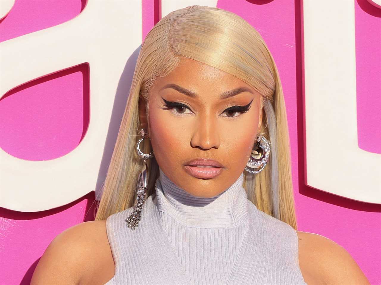 Nicki Minaj, wearing chunky earrings and a purple crop top, poses on the red carpet of the Barbie premiere.