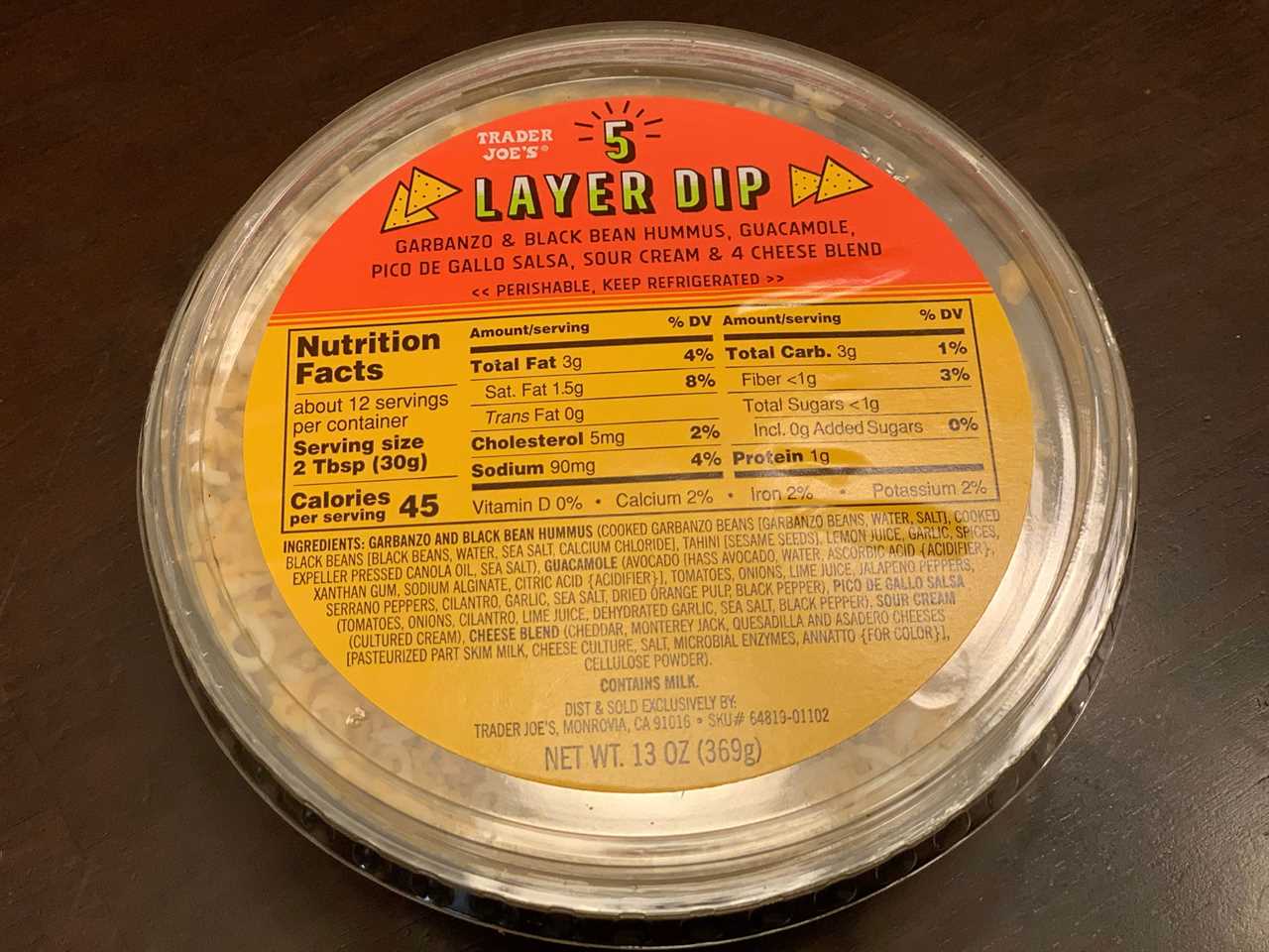 orange and yellow tub of trader joe's 5 layer dip on wood table