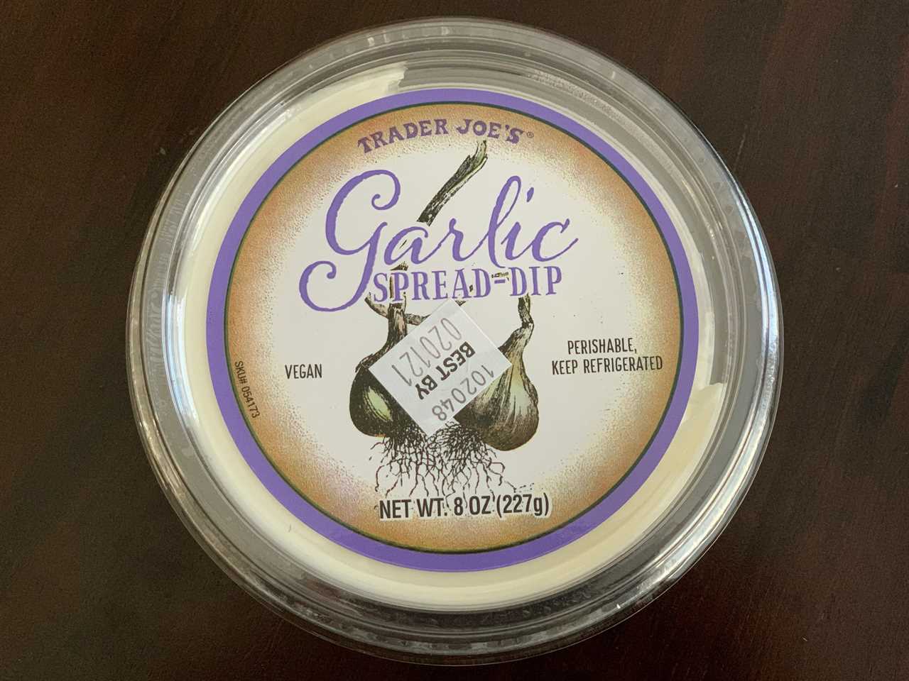 white tub of trader joe's garlic spread dip on wood table