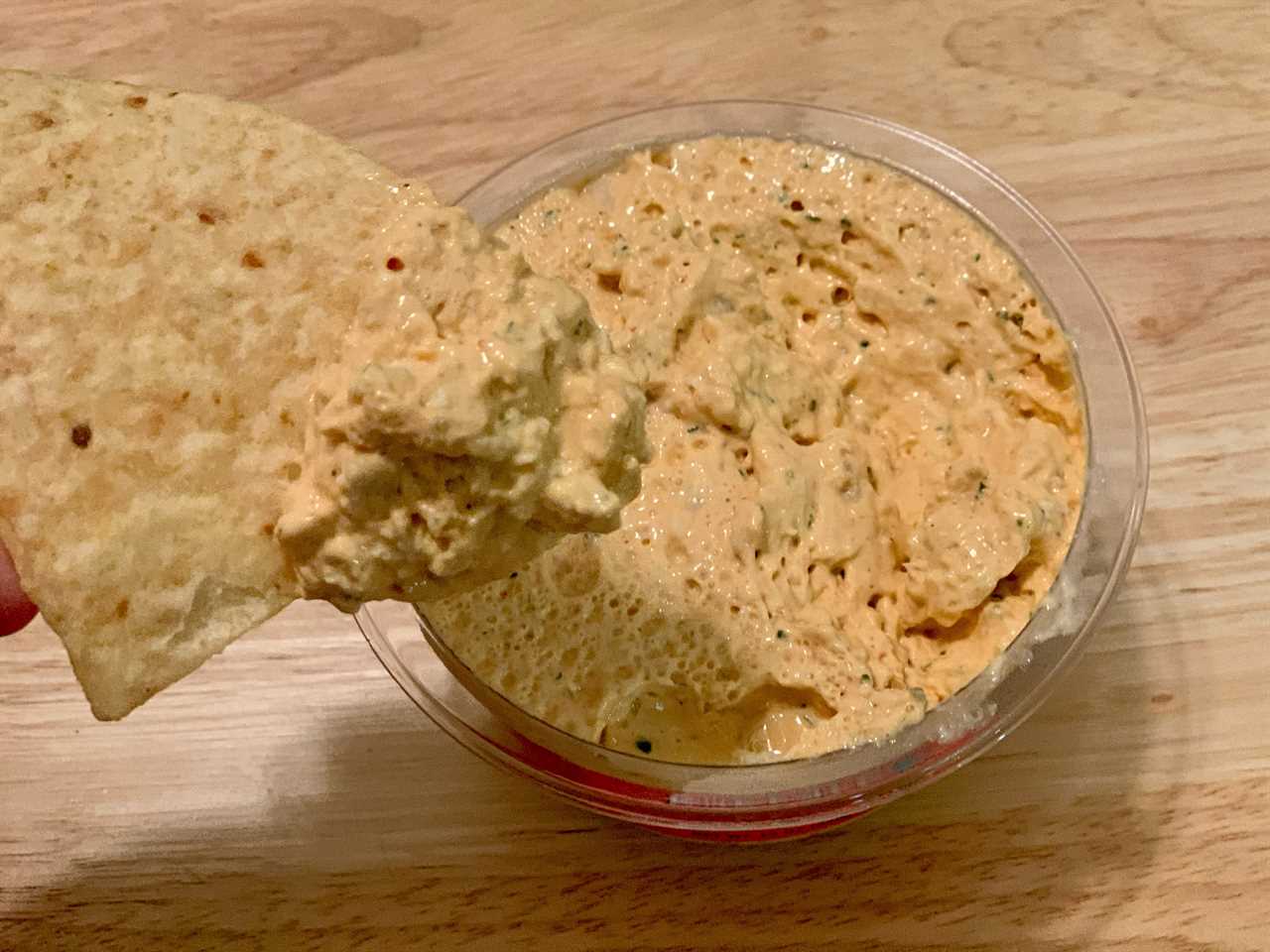 chip dipping into trader joe's buffalo chicken dip on wood table