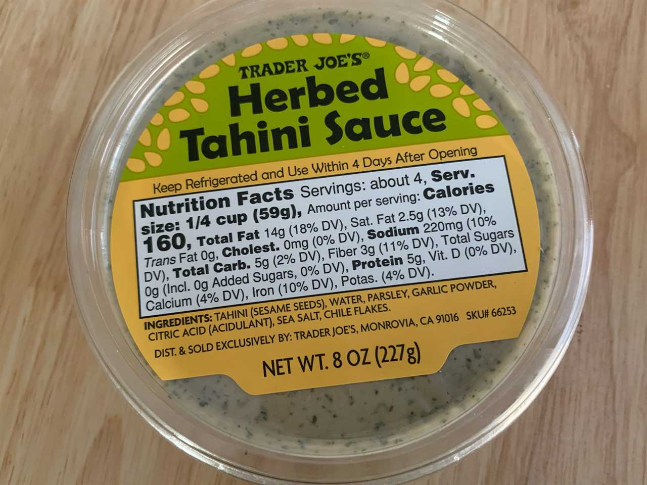 green and yellow trader joe's herbed tahini dip on wood table