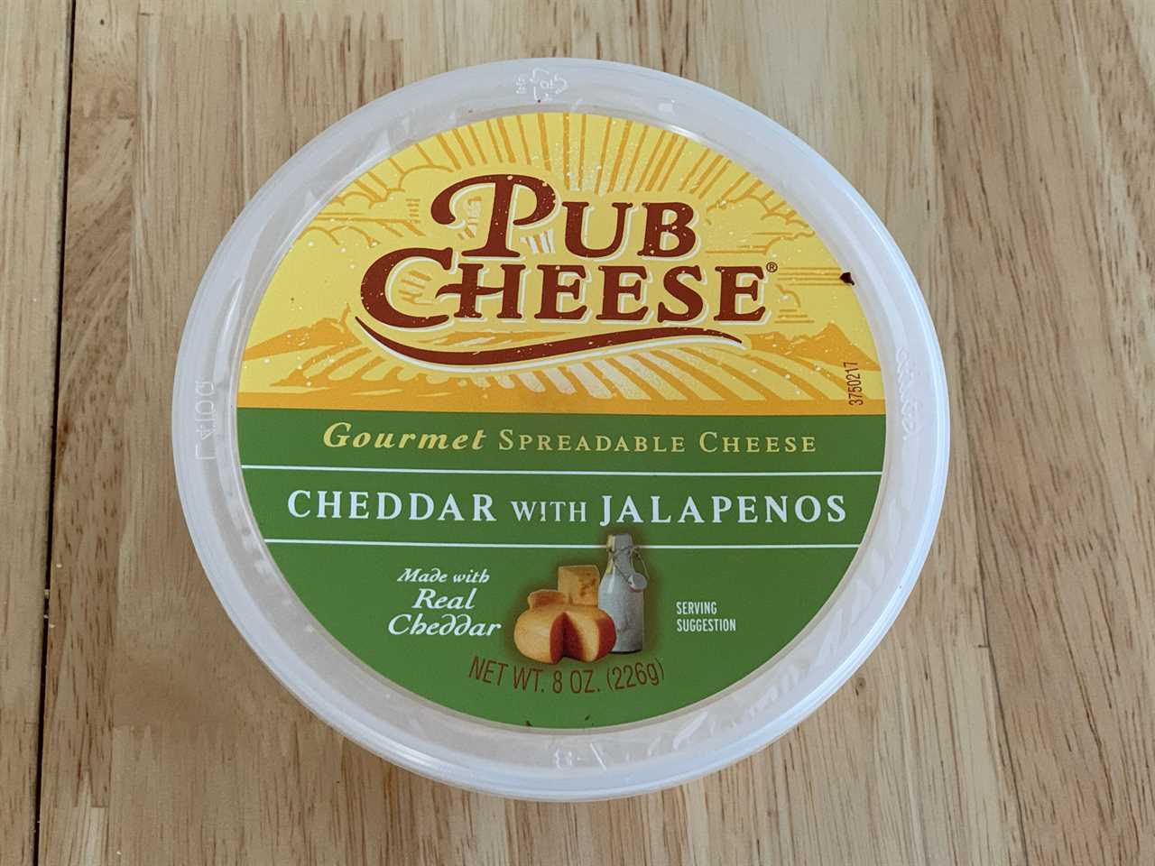 yellow and green tub of trader joe's jalepeno pub cheese dip on wood table