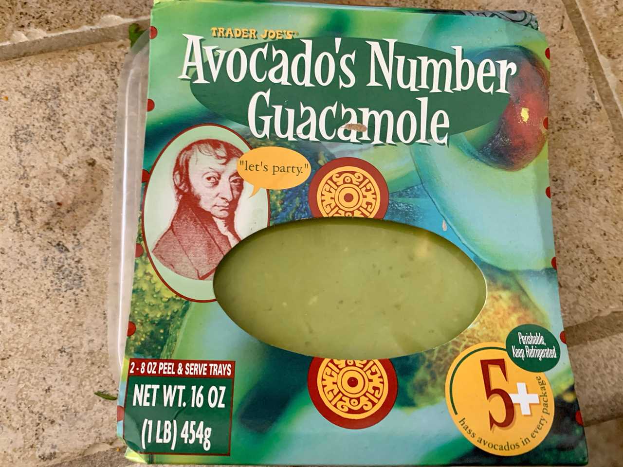 blue and green container of trader joe's avocado number guacamole on tile counter