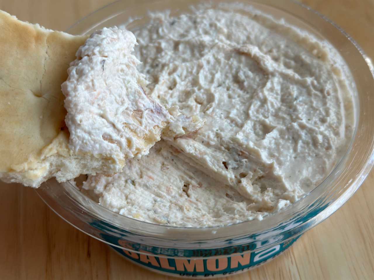 A piece of bread dips into Trader Joe's salmon spread