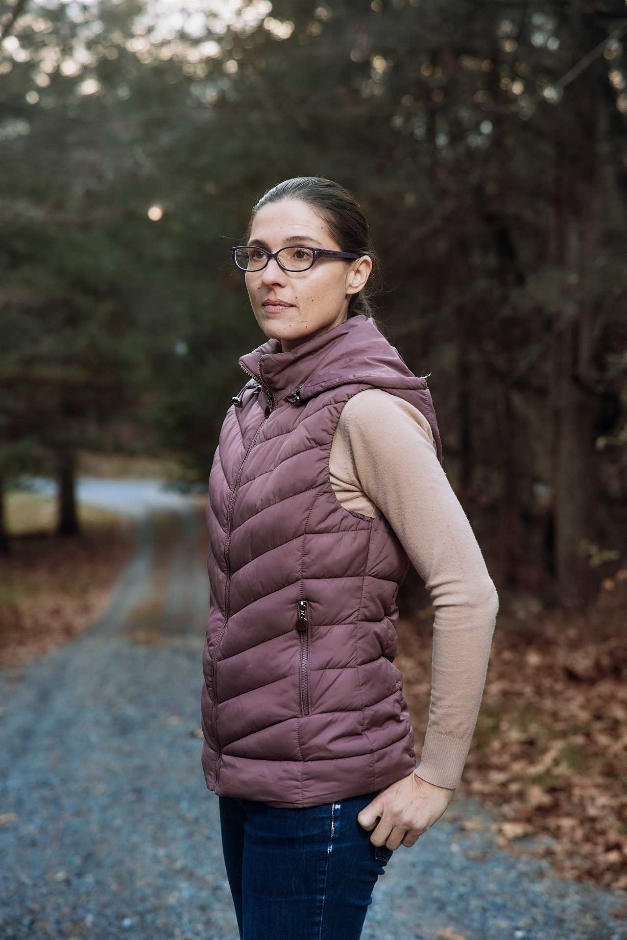 Woman standing in a road in the woods.