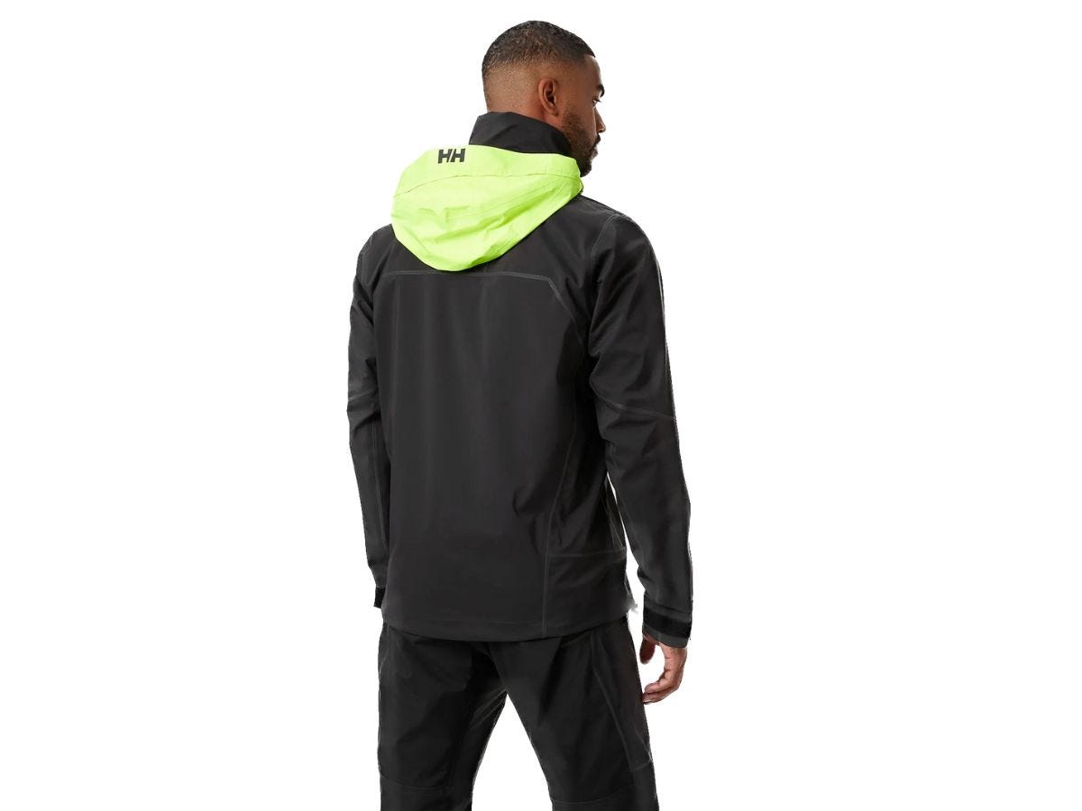 A man wearing a black and bright green rain jacket from Helly Hansen