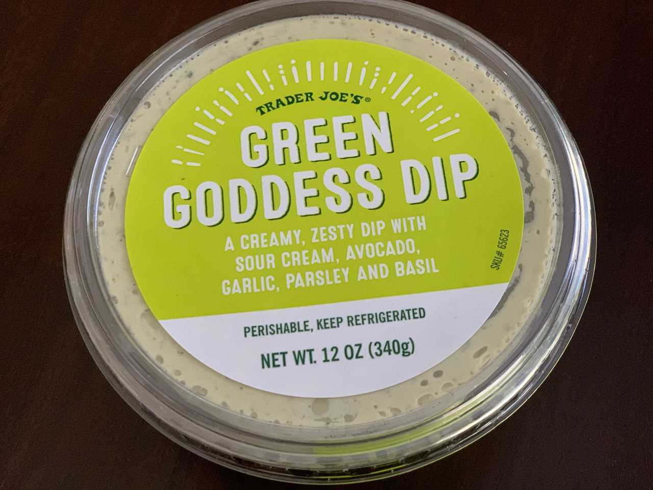 green and white tub of trader joe's green goddess dip on wood table