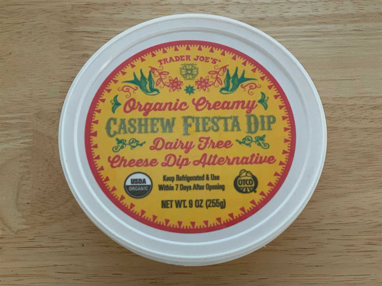 yellow tub of trader joe's cashew fiesta dip on wood table