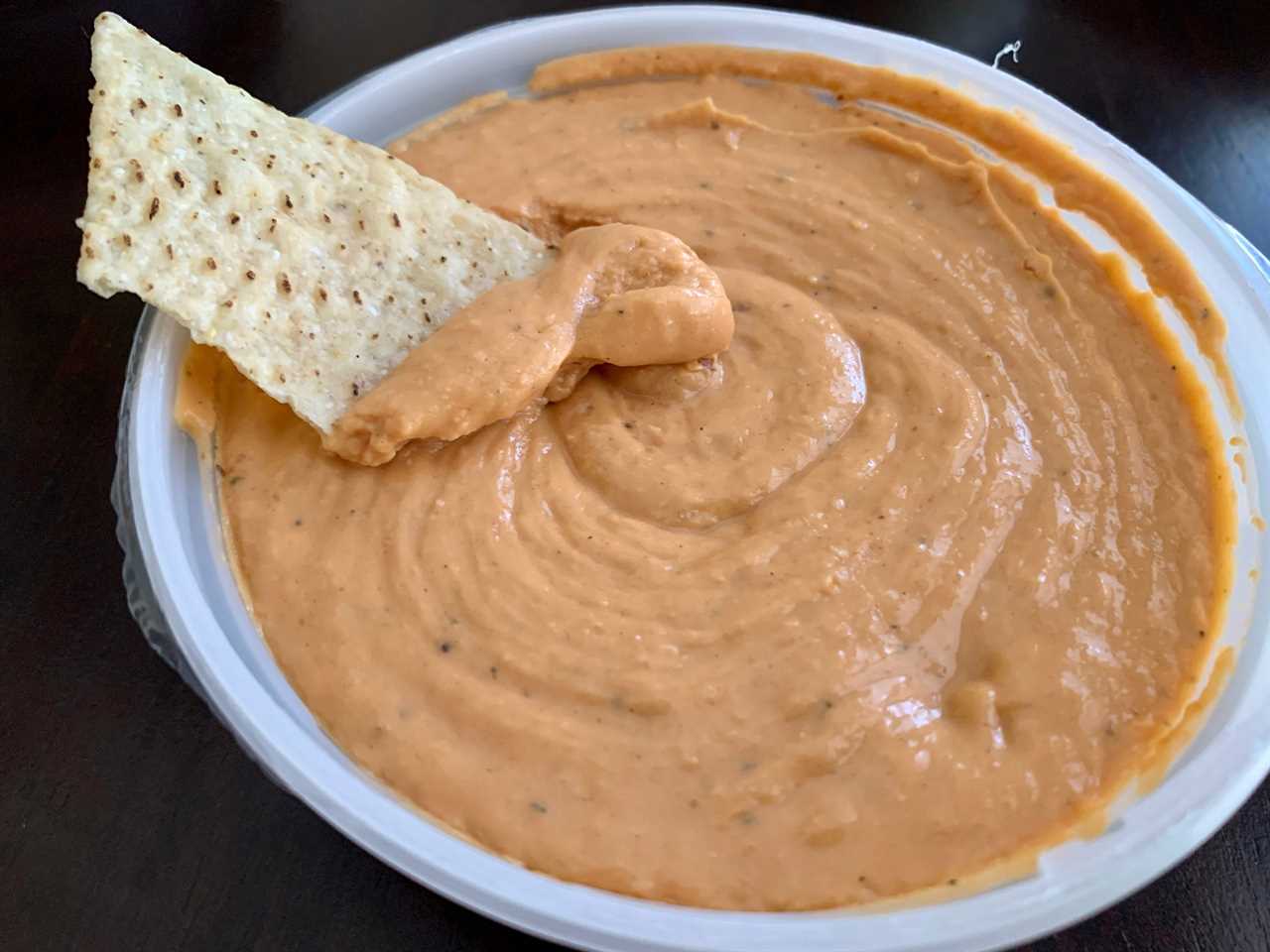 chip dipping into trader joe's tomato basil hummus