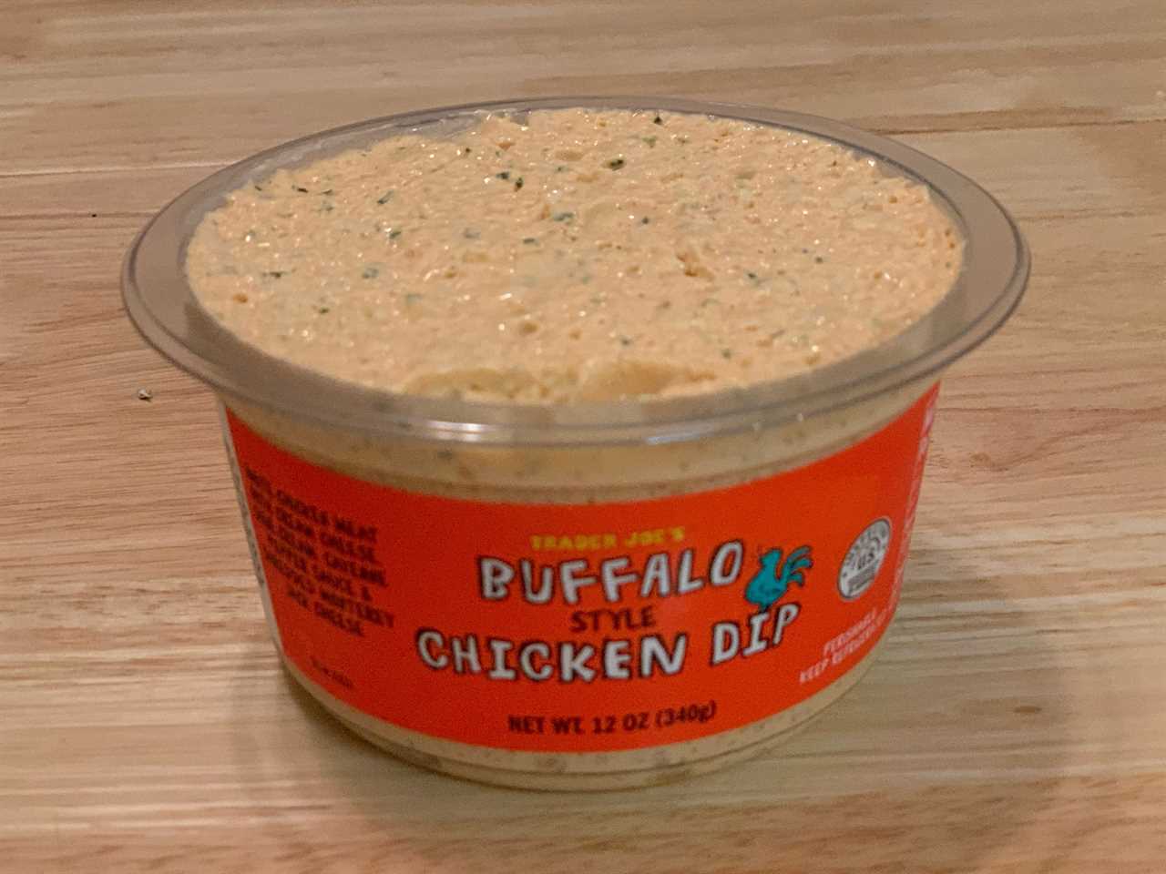 open orange tub of trader joe's buffalo chicken dip on wood table