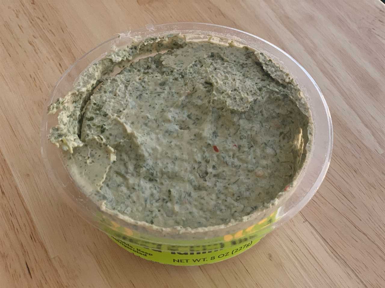 open tub of trader joe's herbed tahini dip on wood table