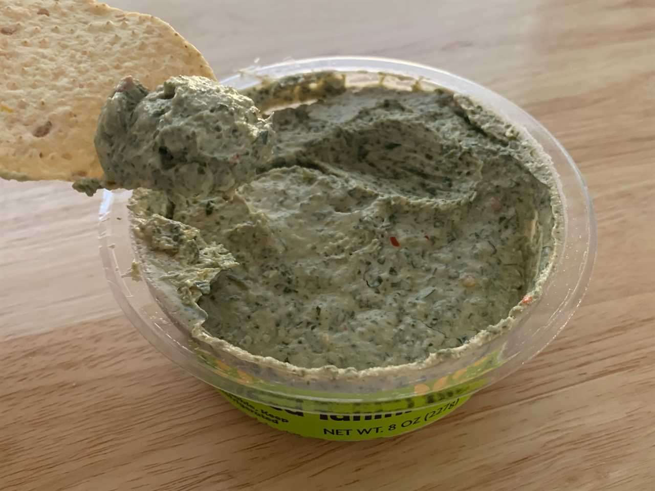 chip dipping into trader joe's herbed tahini dip