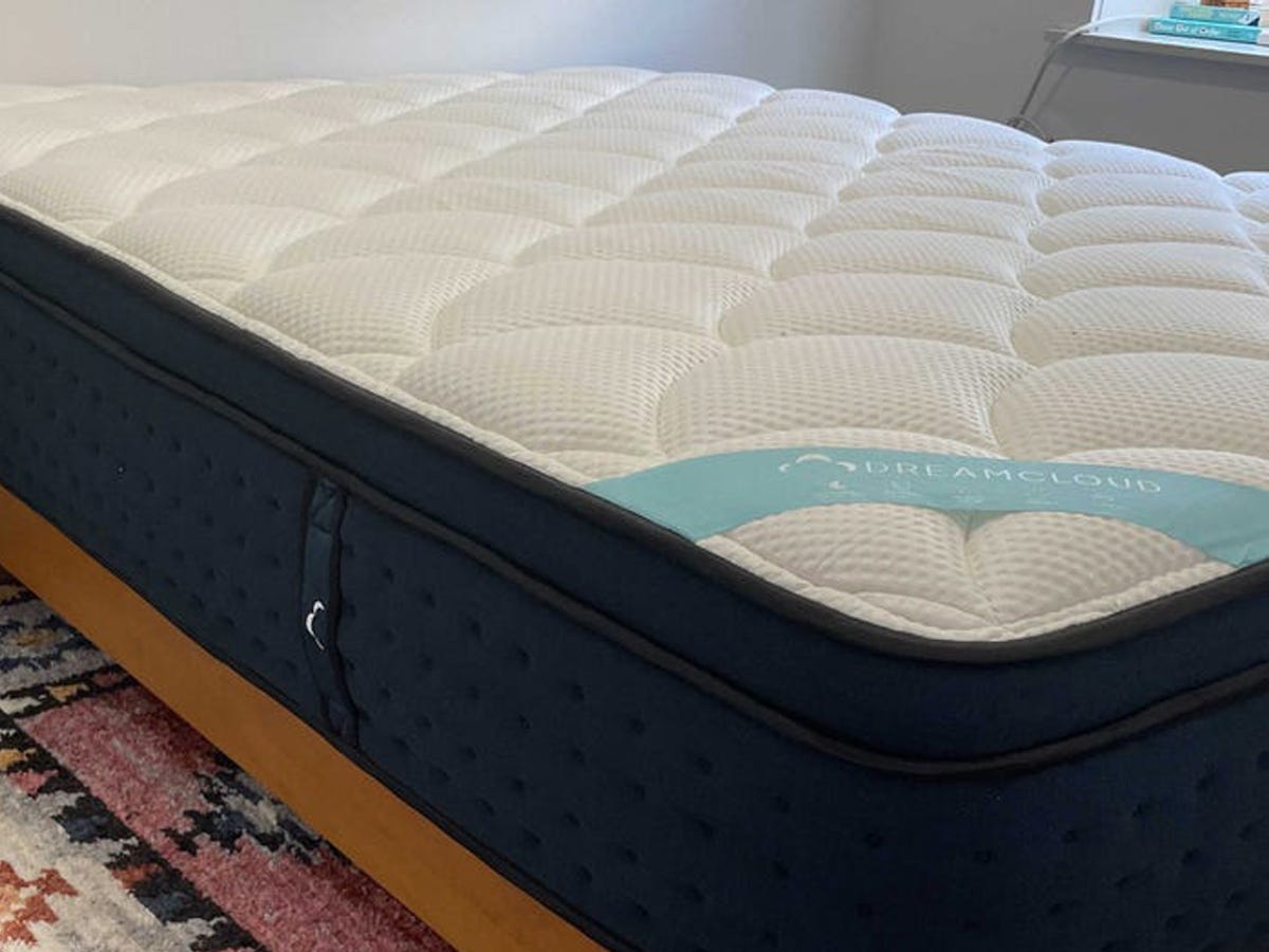 The DreamCloud Premier Hybrid Mattress sits on a bedframe in a bedroom.