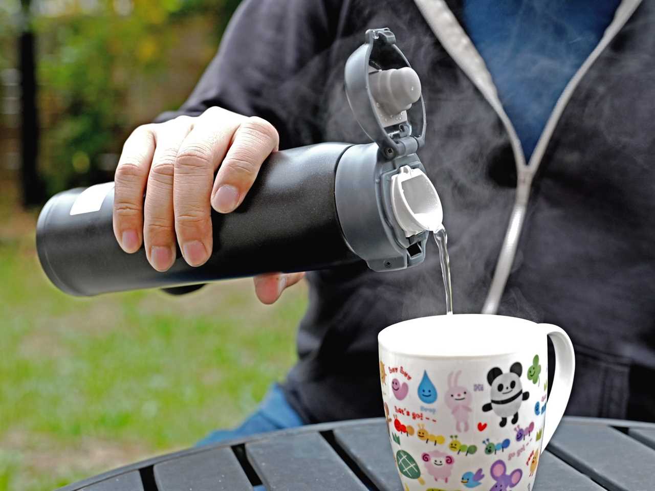 Person pouting water from a Contigo travel mug into a coffee mug.