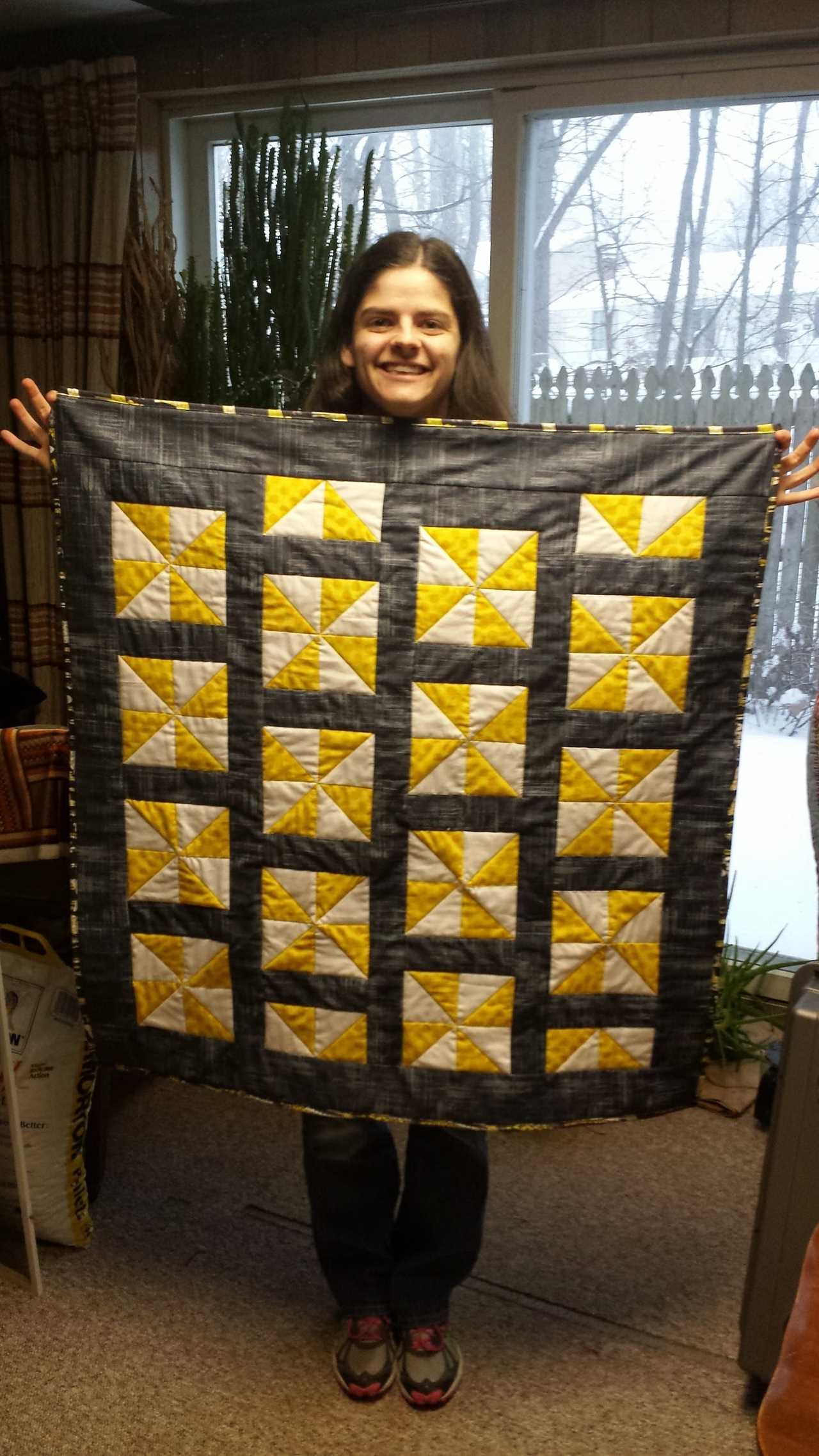 A woman holding a black, white, and yellow quilt.