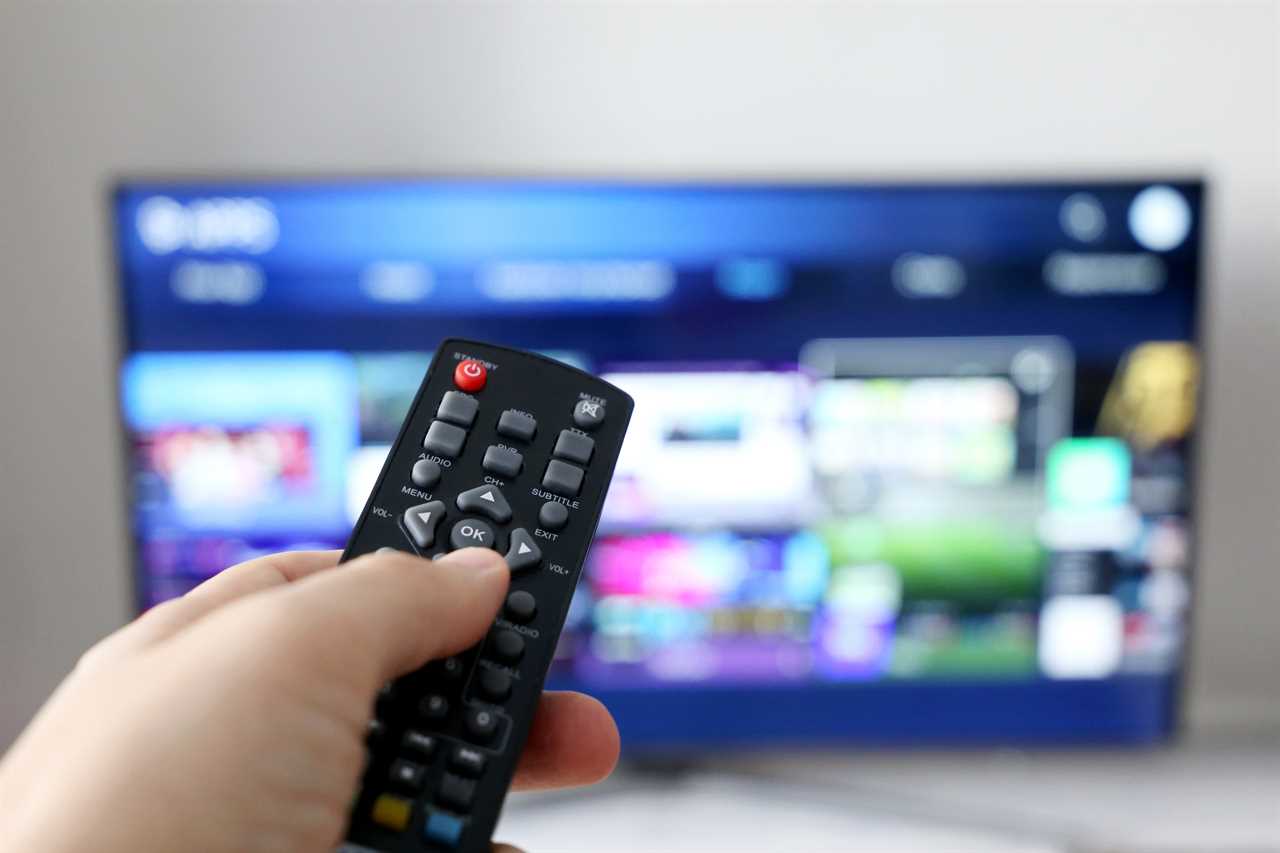 A remote control pointing to a TV set that has apps shown.